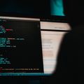 Hackerangriff, Person sitzt an einem Computer und arbeitet an einem Code