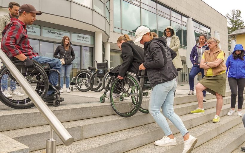 Stephan Gmür (l.) zeigt den Teilnehmenden, wie eine Person im Rollstuhl sicher eine Treppe hinuntergebracht wird.