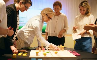 Mit Hilfe eines physischen Holzspielbretts mit einer eingravierten Matrix und dem Einsatz von verschiedenen Bausteinen wird die Strategie greifbar.