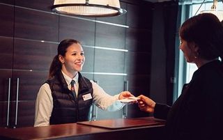 Hoteliere bedient zwei Personen an einem Tresen