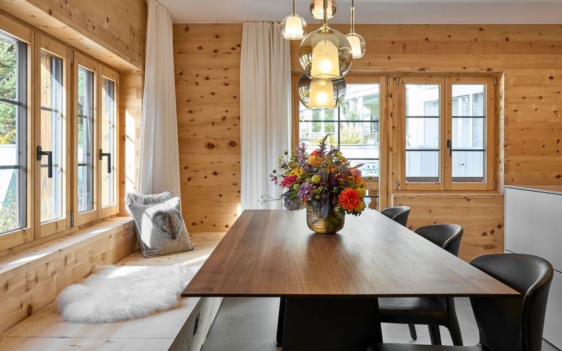 Aufenthaltsraum in einem Holzhaus mit Tisch, Stühlen und Bank