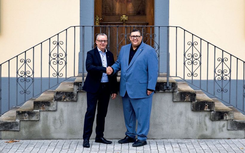 Zwei Personen schütteln sich die Hände vor einer Treppe