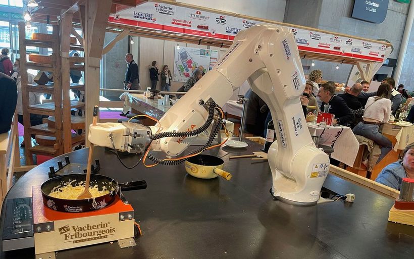Ein weisser Roboterarm bereitet ein Fondue zu.